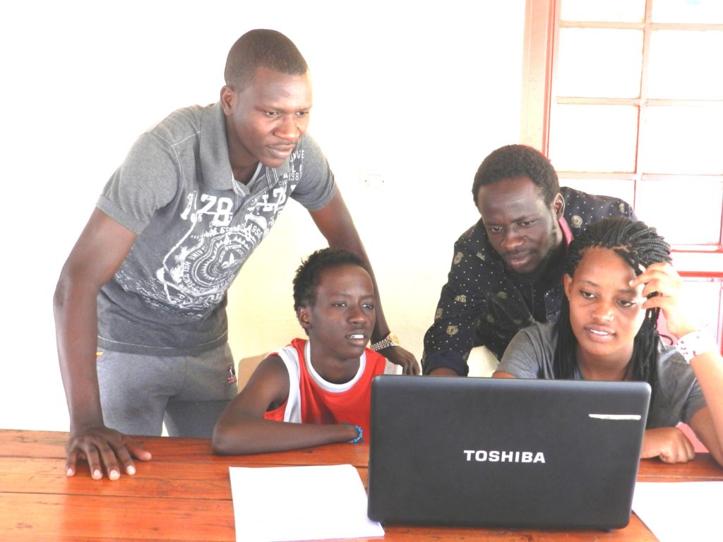 Young-people-learning-how-to-use-a-computer-with-the-help-of-their-elder